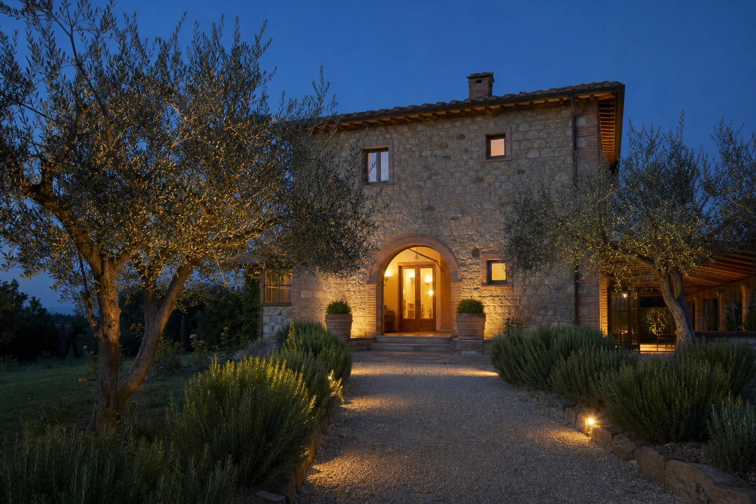 Ingresso illuminato del casale al tramonto tra ulivi e rosmarino