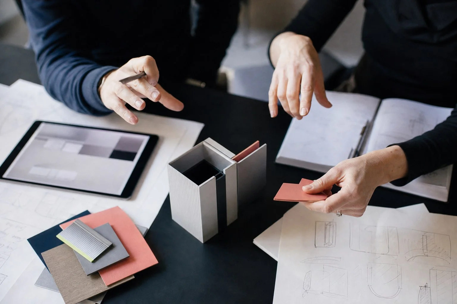 Professionisti confrontano un prototipo e materiali di progetto durante una consulenza