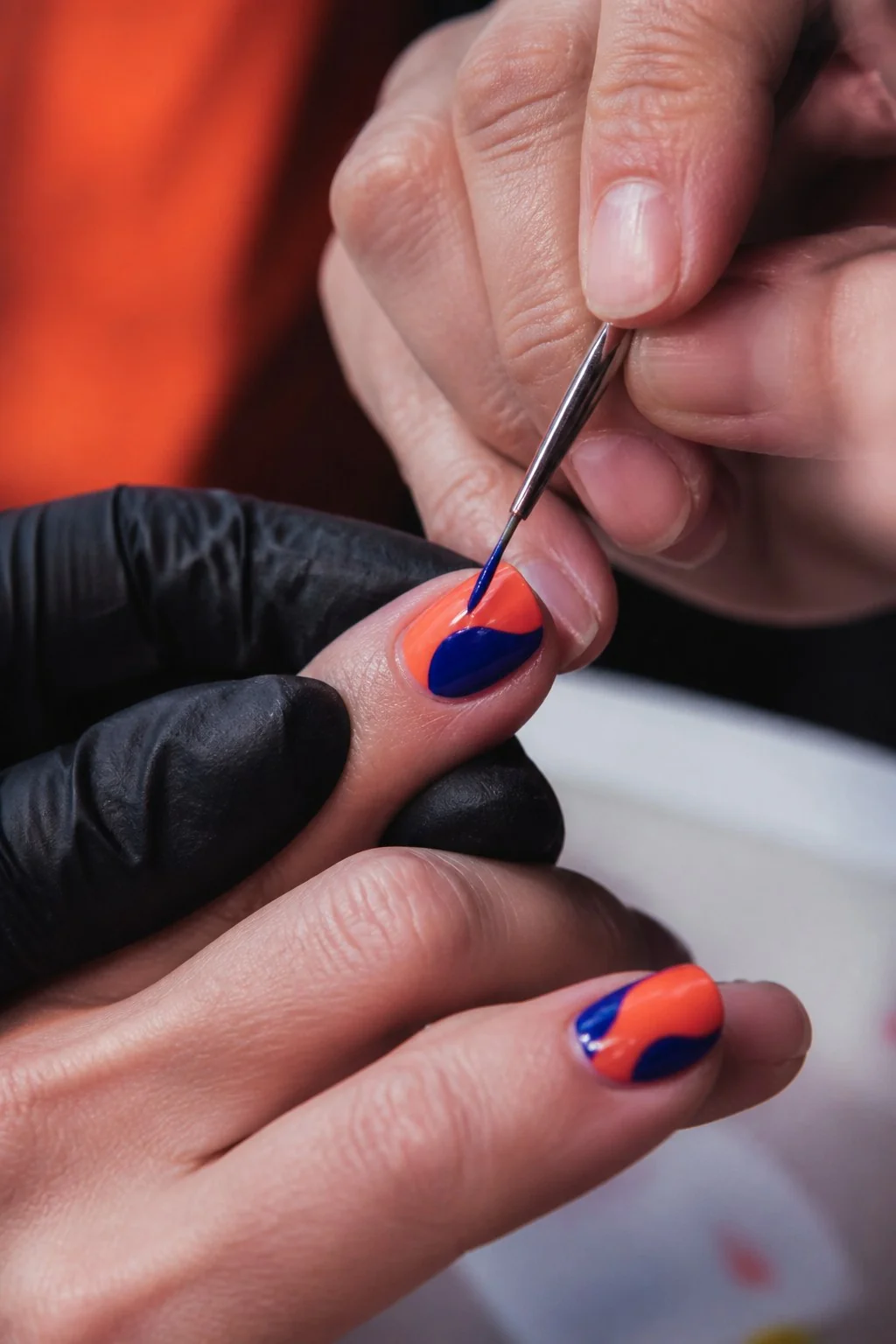 Nail artist dipinge una manicure corallo e blu