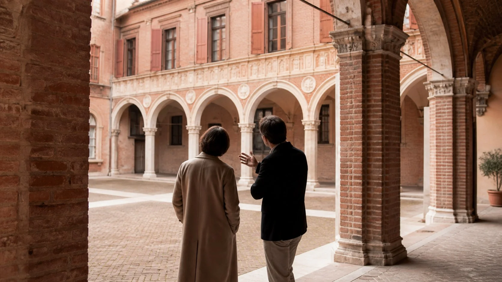Ospite accompagnata da una guida sotto i portici di un palazzo ferrarese