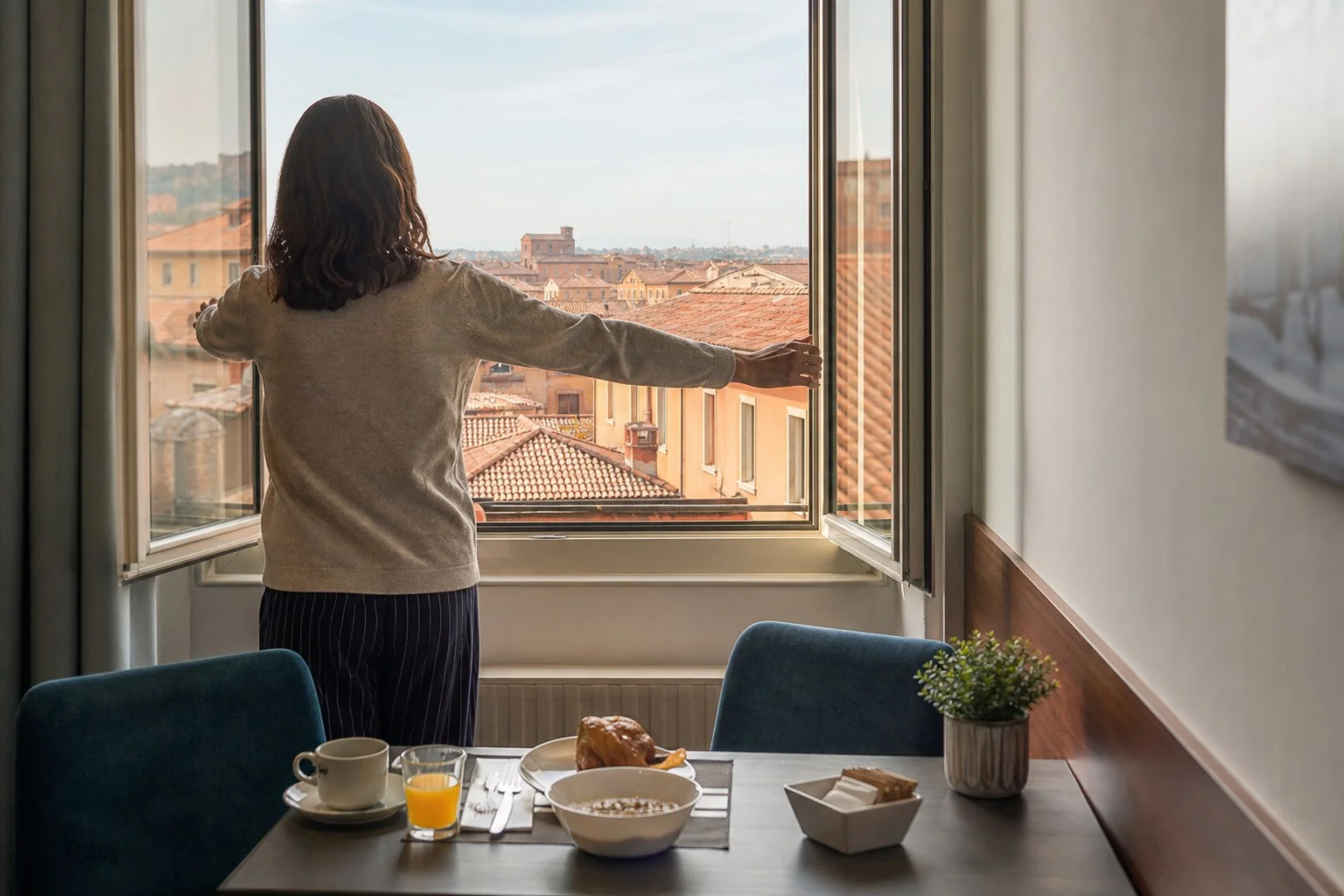 Ospite apre la finestra della sala colazione affacciata sui tetti della città