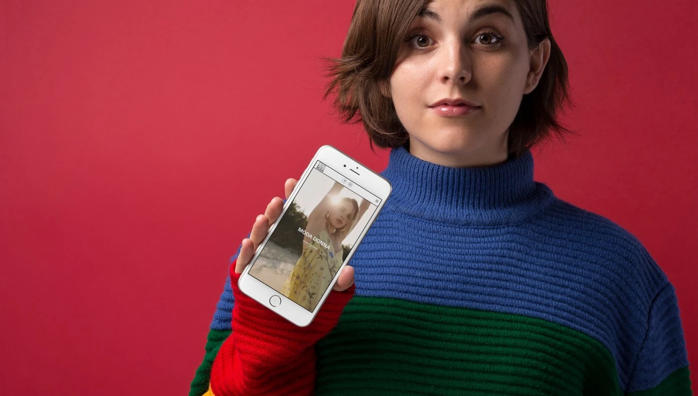 Donna mostra su smartphone un Sito Web personalizzato per Atelier Moda
