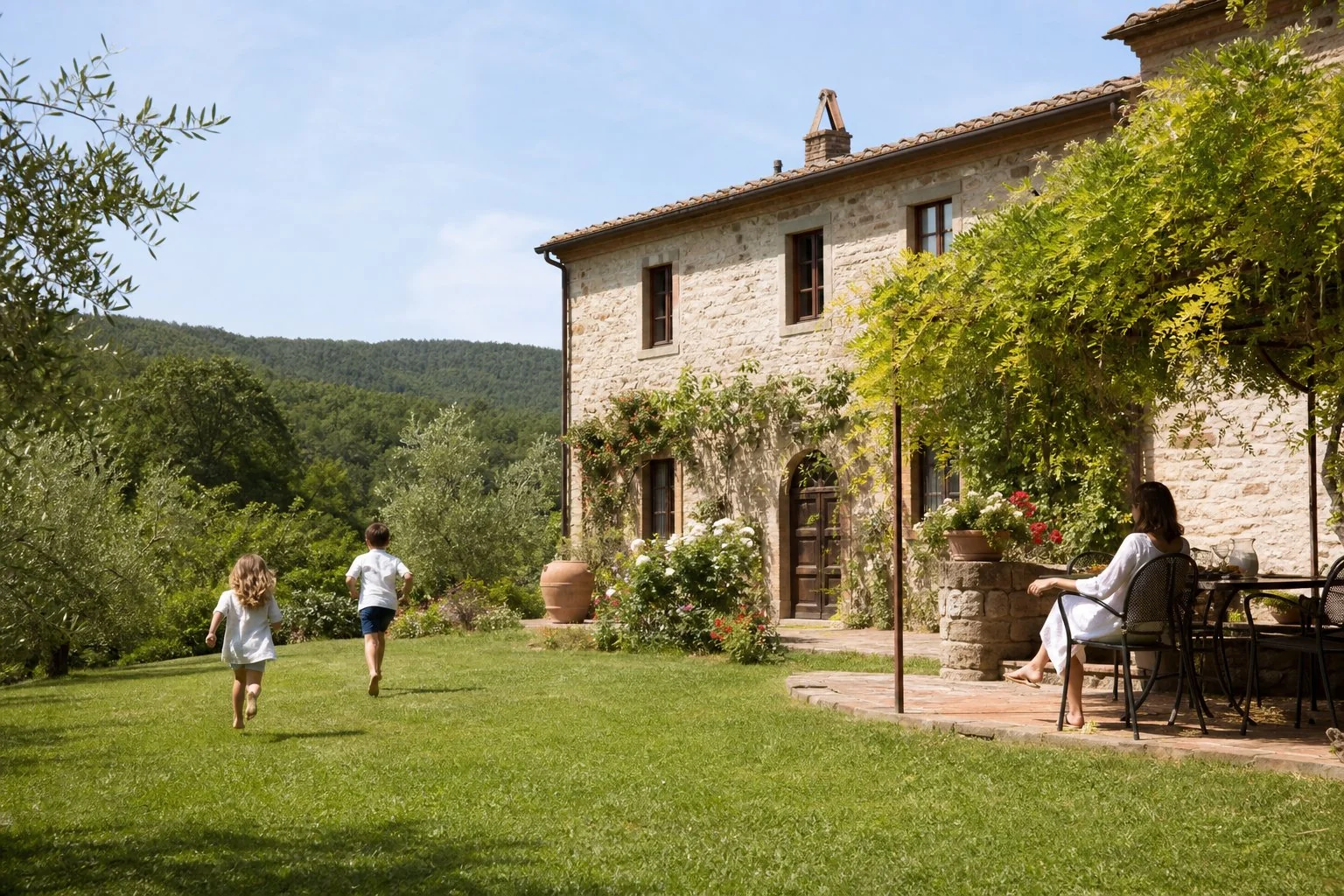 Esterno in pietra di Aia Chiara con prato, bambini e tavolo all'aperto.